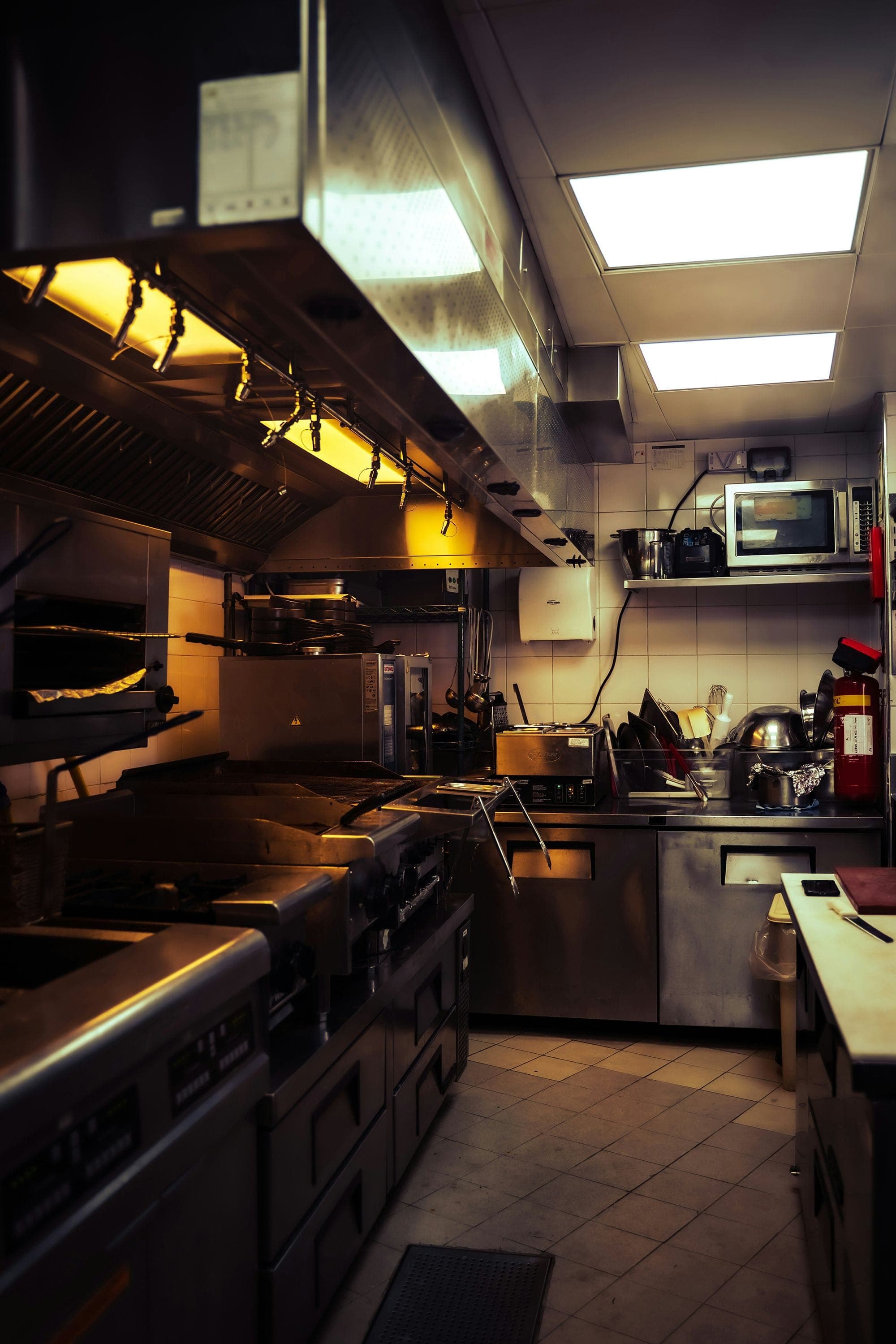 Photograph of an industrial kitchen; above the stove is a series of nozzles that are part of a fire suppression system.